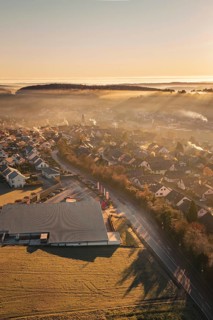 Aerial view of a village in morning fog with autumnal atmosphere and sunlight, Gechingen, Hecken