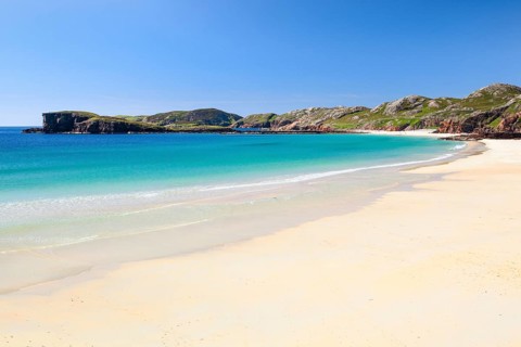 Lonely person on the idyllic sandy beach of Oldshoremore, on the west coast of Scotland