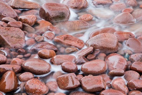 Detail of the swell on a red stone beach on the northwest coast of Scotland