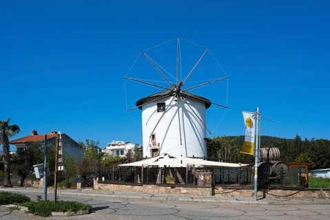 A traditional white windmill with wheels stands under bright blue sky, Cunda windmill, Alibey