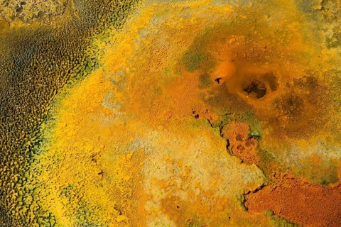 Detailed view of a mineral-rich volcanic landscape in intense shades of orange, geothermal area,