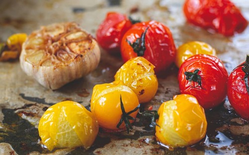 Baked cherry tomatoes, in the oven, on a baking sheet, with olive oil and spices, close-up,