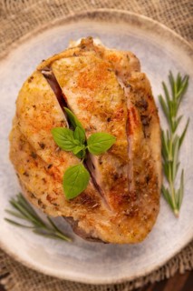 Fried Turkey Thigh with spices and rosemary on plate on brown wooden background and linen textile.