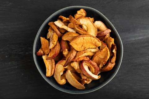 Dried Apples in ceramic bowl on black wooden background. Top view, close up, flat lay. healthy