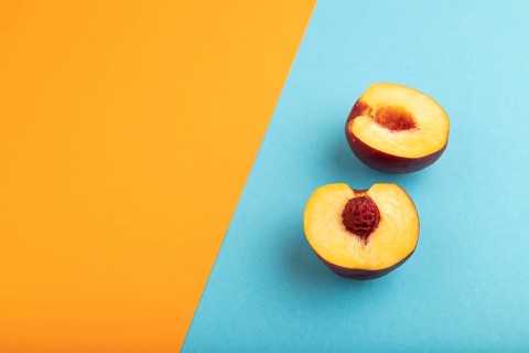 Peach Cut in half on orange and blue paper pastel background. Side view, copy space. healthy food,