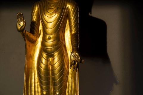 Standing gilded Buddha statue, the right hand (raised, open palm facing outwards) symbolises the