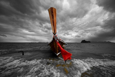 Longtail boat on the beach with dark rain clouds behind it, Koh Ngai island, Andaman Sea, Satun