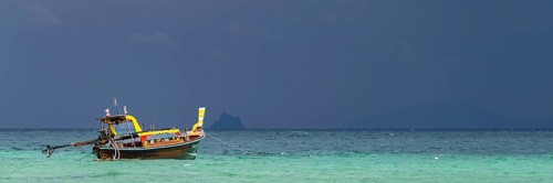 Longtail boat (Thai: Ruea Hang Yao) on the beach, behind it an approaching thunderstorm, Koh Ngai
