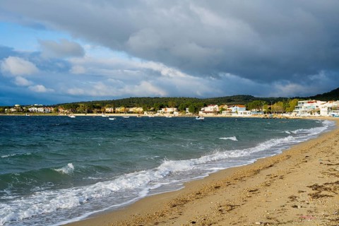 A beach with soft waves, cloudy skies and houses along the coast, beach near GÃ¼zelyali,