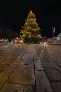 A festively lit Christmas tree at night on a paved square, Aidlingen, Böblingen district, Germany