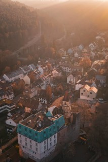 Aerial view of picturesque village in morning light surrounded by forests and hills,