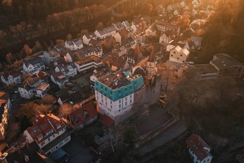 Aerial view of a village in the golden light of sunset, with a distinctive castle, Dillweisenstein,