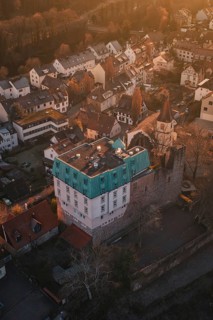 Aerial view of a village with a castle in warm evening light surrounded by trees, Dillweisenstein,