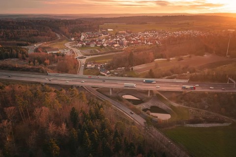 Sunset over a rural village with a motorway leading through fields and forests, A8 motorway,