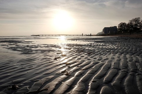 Low tide, wave and ripple patterns in wet sand, long pier in the background, sunrise, Scharbeutz,
