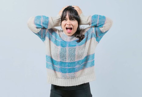 Panicked Asian girl holding her head isolated. Alarmed and worried woman holding her head