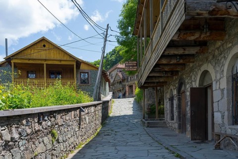 View of a quiet cobblestone street in a village lined with old buildings and green plants, Old