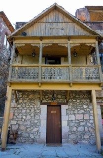 Historic wooden house with carved balcony and stone base, rustic charm, old town, Sharambeyan