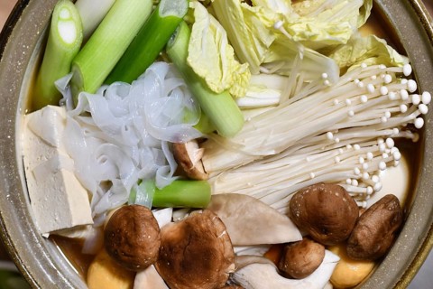 Top view of Japanese nabe or nabemono soup dish with unkooked Chinese cabbage, tofu, enoki and