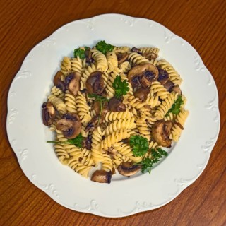 Simple Italian dish pasta fusilli with mushrooms garnished with parsley, vegan cuisine,