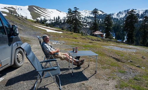 A man relaxing next to a van in a sunny mountain landscape, view from Goderdzi Pass, Ajara region,