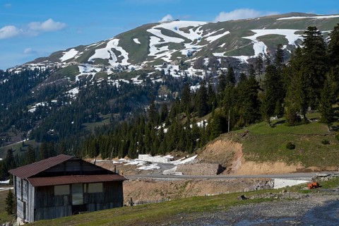 A mountainous landscape with snow-covered hills, forest and a hut in peaceful nature, on the