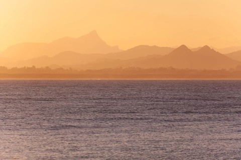View of the ocean and Byron Bay hinterland at sunset. Mt. Warning, Wollumbin National Park over the