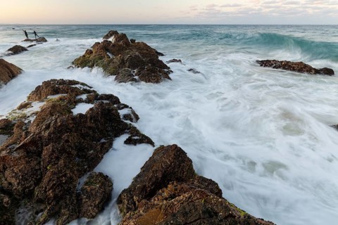 The Cape Byron Lookout at high tide: rocks and anglers in golden light. Byron Bay, New South Wales,