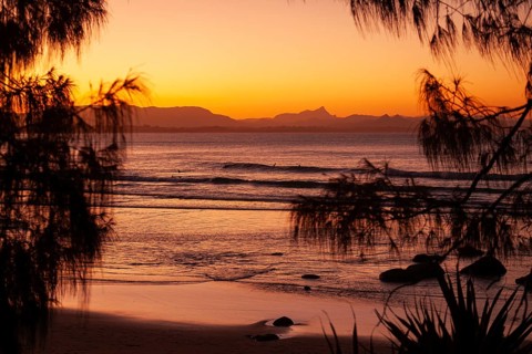 View of the ocean and Wategos Beach on the promenade at sunset. Mt- Warning, Wollumbin in the