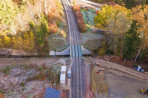 Autumn aerial view of railroad crossing and tracks surrounded by trees, Hermann Hesse Railway bat