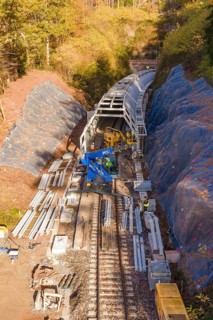 Aerial view of a construction site with railroad tracks and tunnel under construction, Hermann