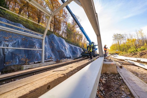 Construction work on a metal structure over railway lines in autumn surroundings, Hermann Hesse