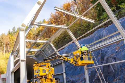Workers on a lift building tunnel surrounded by colorful autumn trees, Hermann Hesse Railway bat