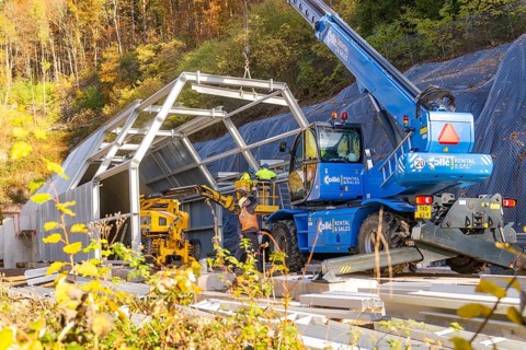 Workers and machines assembling a tunnel surrounded by autumn trees, Hermann Hesse Railway Bat