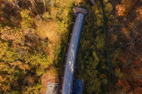 Autumn forest frames a tunnel construction project, shown in a colorful aerial view, Hermann Hesse