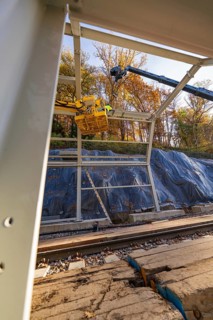 Metal frame construction with crane over tracks in an autumn environment with forest in the