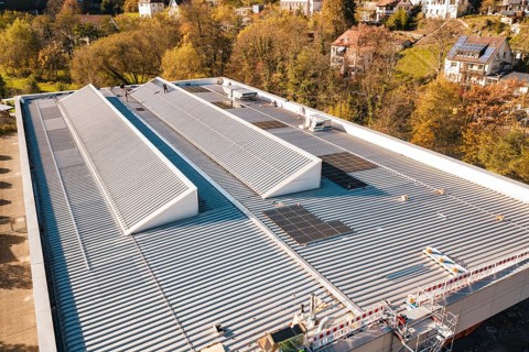 Detailed view of a modern building roof with solar cells, surrounded by trees, PV at Walther