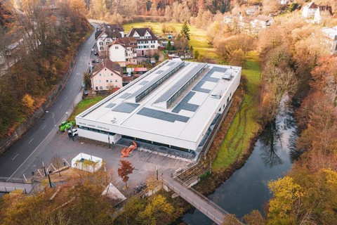 Building with solar panels on the river in an autumnal village, PV at Walther Lindner Sporthalle
