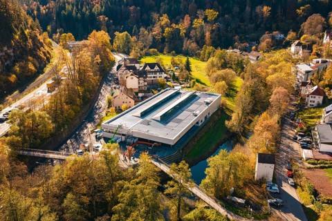 Building with solar panels in the middle of a picturesque autumn landscape with river and forest,