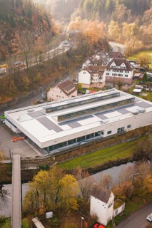 Building with solar panels in an autumn landscape, surrounded by village houses, PV at Walther