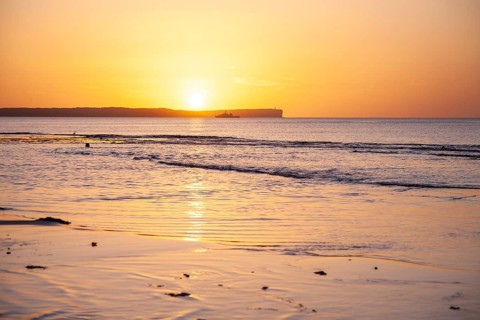 Sunrise over Jervis Bay â€” View of Point Perpendicular lighthouse. A ship on the horizon