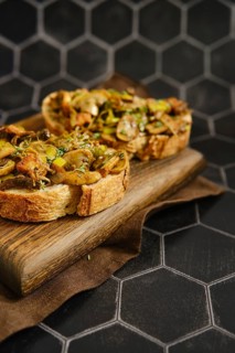 A delicious mushroom sandwich is arranged on a wooden board. The sandwich includes honey mushrooms,