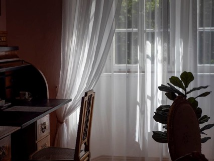 White tulle curtains in antique room with old secretary furniture and chair