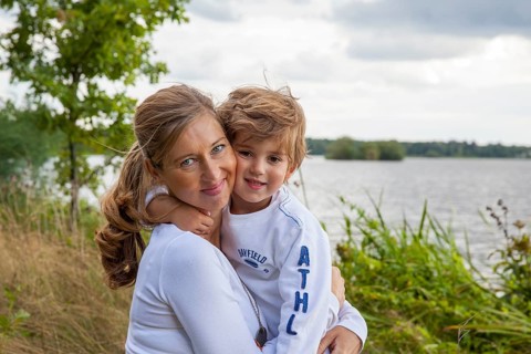 Pregnant woman with little boy at lake, mom and child hugging