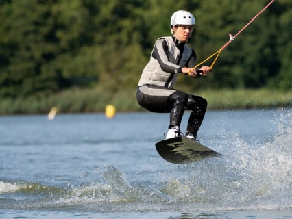 Young man with wakeboard, jumping on water, water sports, wake park