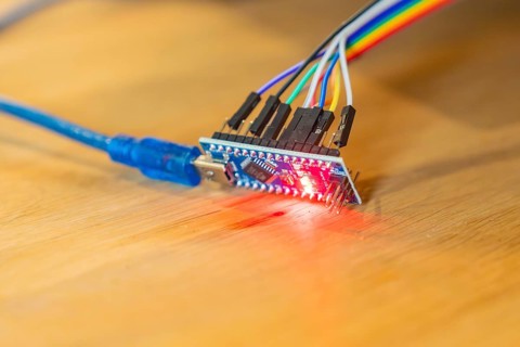 Small circuit board glows red, connected to USB cable, on wooden table, Jugend Forschungszentrum