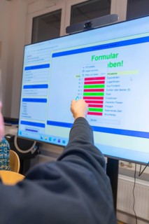 Person pointing at digital forms on a large screen, Jugend Forschungszentrum Nagold, Calw district,