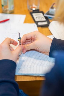 Circle holding hands while working on a notebook, Jugend Forschungszentrum Nagold, Calw district,
