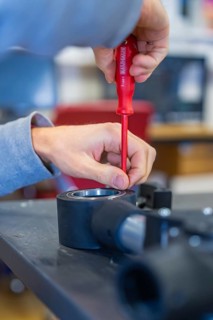 Person uses screwdriver to mount on a technical device, Jugend Forschungszentrum Nagold, Calw