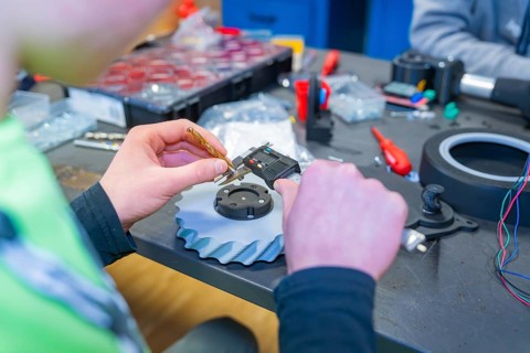 Person measuring gear at a table full of tools, Jugend Forschungszentrum Nagold, Calw district,